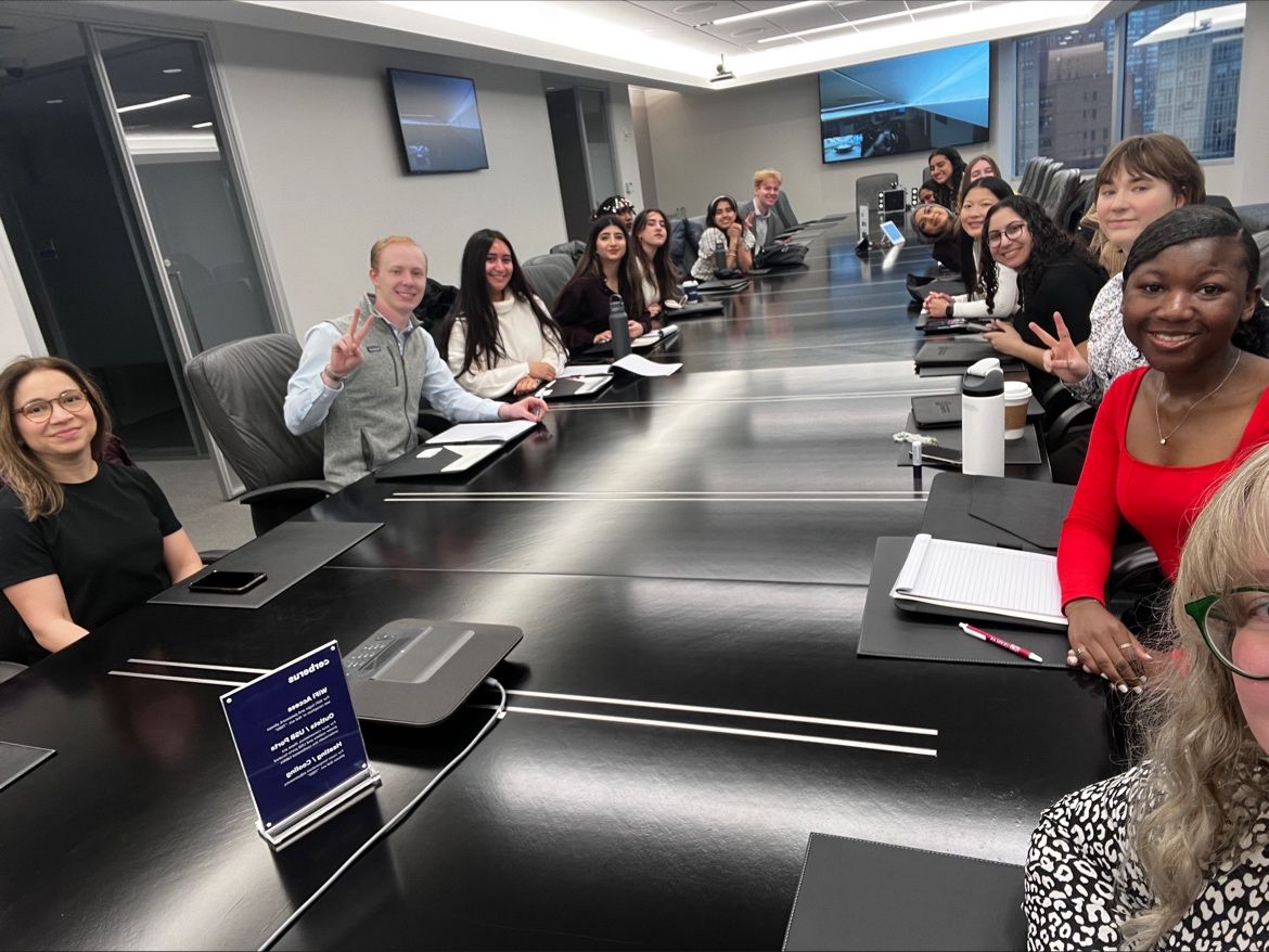 A group of Quinaln Ramble students pose for a photo around a conference table at Cerberus Capital Management in New York City.